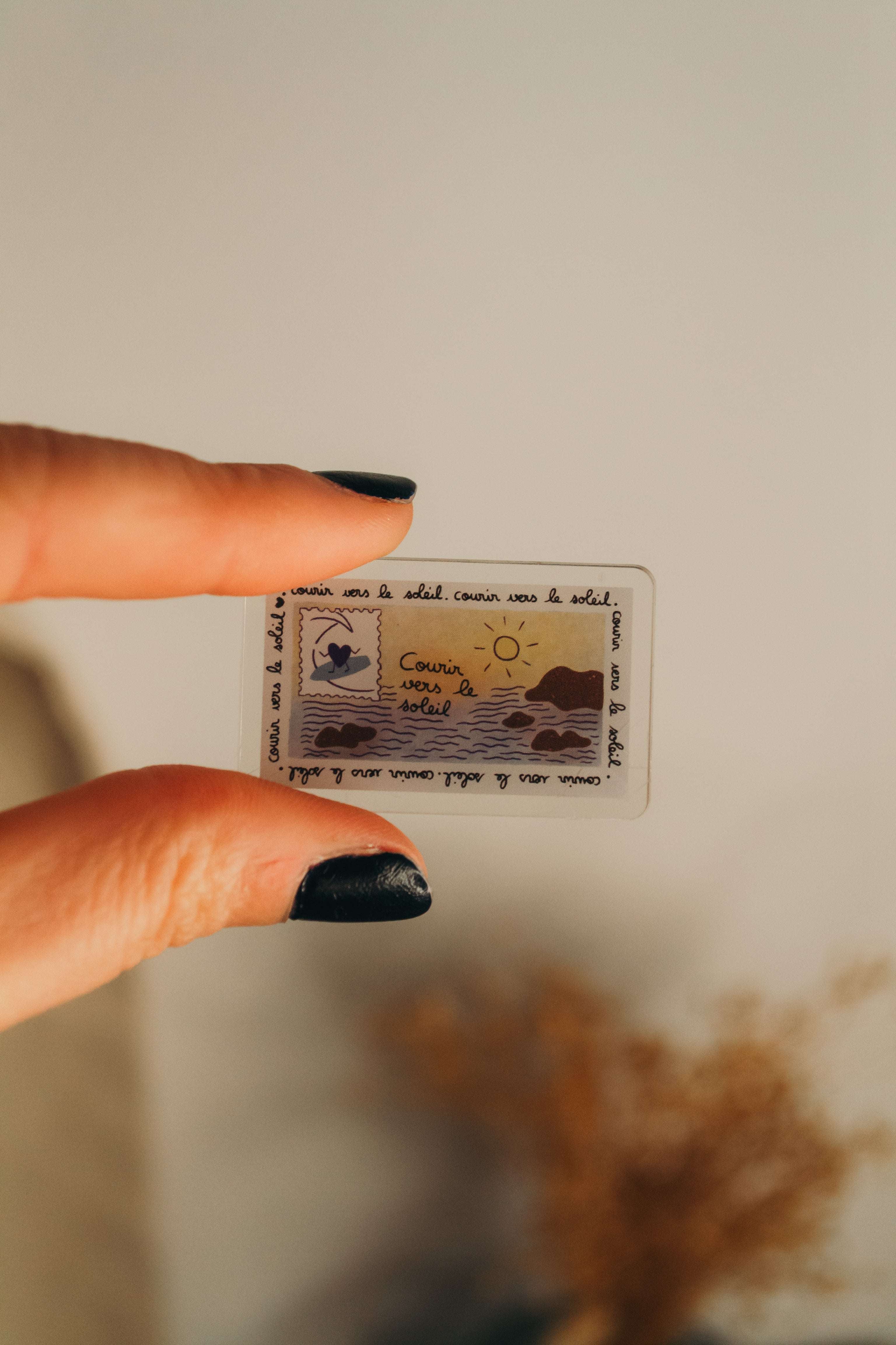 Main qui tient badge en acrylique avec écrit "courir vers le soleil"